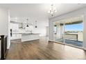 Bright open-concept kitchen with white cabinets, black countertops, stainless steel appliances, and hardwood flooring at 17125 W 92Nd Loop, Arvada, CO 80007