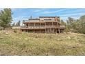 Expansive tiered deck overlooking hillside, supported by sturdy beams, and surrounded by rocks and grasses at 3961 Mossy Rock Ln, Evergreen, CO 80439