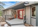 Inviting covered front porch with stone accents and a striking red glass-paned front door at 3961 Mossy Rock Ln, Evergreen, CO 80439