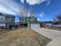 Inviting two-story green home with a two-car garage, driveway, and well-maintained lawn under a blue sky at 12025 Monaco Dr, Brighton, CO 80602