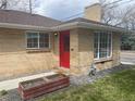 Attractive brick house featuring a vibrant red front door and manicured landscaping at 799 N Holly St, Denver, CO 80220