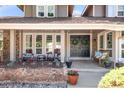 Inviting covered front porch with stone detailing, comfortable seating, and stylish double door entrance at 5557 E Links Cir, Centennial, CO 80122