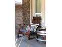 Cozy front porch detail showcasing comfortable wooden rocking chair and an accent side table at 5557 E Links Cir, Centennial, CO 80122
