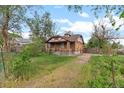 View of the side and front of the brick single-Gathering home with overgrown lawn at 2701 W Mississippi Ave, Denver, CO 80219
