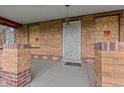 Covered porch area with brick columns, a metal security door, and boarded windows at 2701 W Mississippi Ave, Denver, CO 80219