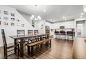 Open-concept dining area with a large wooden table, bench seating, and modern chandelier adjacent to a bright kitchen at 18189 House Finch Ln, Parker, CO 80134