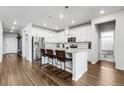 Bright open kitchen features white cabinetry, stainless steel appliances, an island with seating and modern pendant lights at 18189 House Finch Ln, Parker, CO 80134