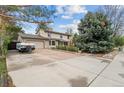 Charming two-story home with an attached garage and spacious driveway bordered by mature trees and landscaping at 930 S Dayton St, Denver, CO 80247