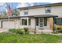 Charming two-story home featuring an attached garage, well-kept lawn, and landscaped garden beds at the front entrance at 930 S Dayton St, Denver, CO 80247