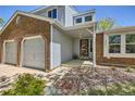 Close-up of a home's entrance showing a covered porch, brick accents, and attached two-car garage at 5046 S Evanston St, Aurora, CO 80015