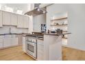 Well-appointed kitchen with stainless steel appliances, custom cabinets, a kitchen island, and open shelving for storage at 1521 Central St # 3C, Denver, CO 80211