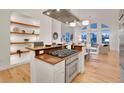 Open kitchen with stainless steel appliances, wooden shelves, and views of the living room at 1521 Central St # 3C, Denver, CO 80211