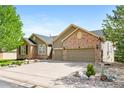 Beautiful home showcasing a manicured front yard, mature trees, brick accents, and attached two car garage at 7120 Red Mesa Dr, Littleton, CO 80125