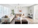 Bright living room featuring shuttered windows, neutral furniture, an elegant chandelier, and a stylish area rug at 7154 S Hudson Cir, Centennial, CO 80122