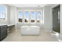 Bright bathroom featuring a soaking tub, vanity area, tiled floors, and a glass enclosed shower at 3378 Backdrop Ct, Castle Rock, CO 80108