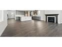 Open-concept living space with dark wood floors, flowing from a modern kitchen to a cozy fireplace area at 3378 Backdrop Ct, Castle Rock, CO 80108