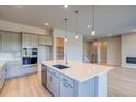 Elegant kitchen boasts quartz island with sink, stainless appliances, modern cabinetry and wood flooring for a stylish design at 8606 Hotchkiss St, Littleton, CO 80125
