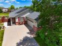 Aerial shot of a ranch-style home with a spacious driveway, well-kept lawn, and partial view of a green space at 13088 Jersey St, Thornton, CO 80602