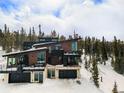 Stylish home with a modern design and expansive windows, blending seamlessly into a snowy, wooded landscape at 436 N Fuller Placer Rd, Breckenridge, CO 80424