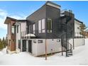 Contemporary home featuring dark siding, balconies, a spiral staircase, and large windows surrounded by snow at 436 N Fuller Placer Rd, Breckenridge, CO 80424