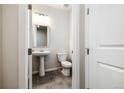 Clean half bathroom with a pedestal sink, white toilet, and a modern light fixture at 8609 Cheraw St, Littleton, CO 80125