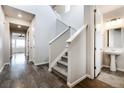 Bright hallway featuring hardwood floors, a staircase with white railings, and a glimpse of a bathroom at 8609 Cheraw St, Littleton, CO 80125