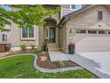 Inviting front entrance with brick facade, arched doorway, flower pots, and well-maintained landscaping at 989 Graland Pl, Highlands Ranch, CO 80126