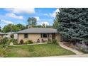 Charming brick home featuring a well-manicured lawn, mature trees, and a cozy front porch at 1217 Lincoln St, Longmont, CO 80501