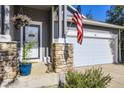 Inviting front porch showcasing stone accents, hanging flower baskets, and an American flag at 12 Apache Plume St, Brighton, CO 80601