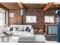 Inviting living room featuring exposed brick walls, wooden beams, and a stylish white sectional sofa at 3733 N Franklin St, Denver, CO 80205