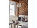 Bright living space with exposed brick, large window, white sofa with decorative pillows, and modern coffee table at 3733 N Franklin St, Denver, CO 80205