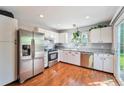 Bright kitchen with stainless steel appliances, white cabinets, hardwood floor and backyard view at 19523 E Buchanan Pl, Aurora, CO 80011