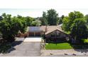 An aerial view of a stone house with solar panels, mature trees, and a well-kept lawn at 8644 S Brentwood St, Littleton, CO 80128
