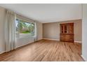 Bright living room with hardwood floors, large window with sheer curtains, and an antique wood hutch at 7425 S Dexter St, Centennial, CO 80122
