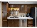 Close up of kitchen featuring stainless steel appliances, tile counter tops, and dark wood cabinets at 12476 W Nevada Pl # 106, Lakewood, CO 80228
