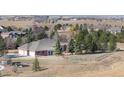 Rear aerial view of a brick home featuring an attached three-car garage and fenced in area at 18399 Wagon Trl, Mead, CO 80542