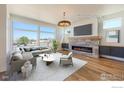 Bright living room with a stone fireplace, hardwood floors, and large windows offering scenic views at 2305 Glacier Ct, Lafayette, CO 80026