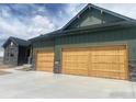 Spacious three-car garage with natural wood doors and concrete driveway at 1366 Eliza Ave, Berthoud, CO 80513