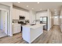 Bright kitchen with white cabinets, stainless steel appliances, a center island, and hardwood flooring at 776 Griffith St, Lochbuie, CO 80603