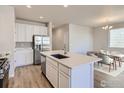 Modern kitchen with stainless steel appliances, white cabinets, and a large island, open to the dining area at 776 Griffith St, Lochbuie, CO 80603