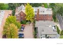 Aerial view of a brick apartment building with ample parking and surrounding greenery at 1515 E 8Th Ave # 1, Denver, CO 80218