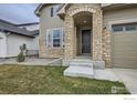 Stylish home entrance with stone archway, concrete steps, and tidy landscaping at 3140 Newfound Lake Rd, Berthoud, CO 80513