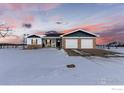 Charming home features brick accents, an attached two-car garage, and is surrounded by a snow-covered lawn at 11499 County Road 40.5, Platteville, CO 80651