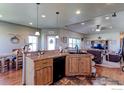 Open-concept kitchen featuring wood cabinets, black appliances, and seamless flow into the adjacent living area at 11499 County Road 40.5, Platteville, CO 80651