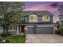 Two-story home with gray siding, two-car garage, and landscaped yard at 6850 Sage Ave, Firestone, CO 80504