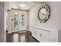 Bright entryway featuring a decorative mirror, a white storage cabinet, and an exterior door with glass panels at 775 Longs Peak Dr, Erie, CO 80516