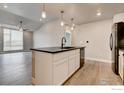 Open-concept kitchen with an island bar, stainless steel dishwasher, and black countertops at 265 High Point Dr # 203, Longmont, CO 80504