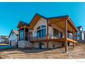 Stunning modern home with a mix of vertical and horizontal siding, stone accents, a covered deck, and pristine landscaping at 1385 Art Dr, Berthoud, CO 80513
