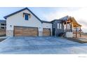 Modern home with a spacious three car garage featuring stylish wood doors and stone accents on the exterior at 1385 Art Dr, Berthoud, CO 80513