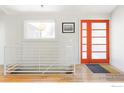 Bright entryway with staircase, orange door, and hardwood floors at 7705 Baseline Rd, Boulder, CO 80303